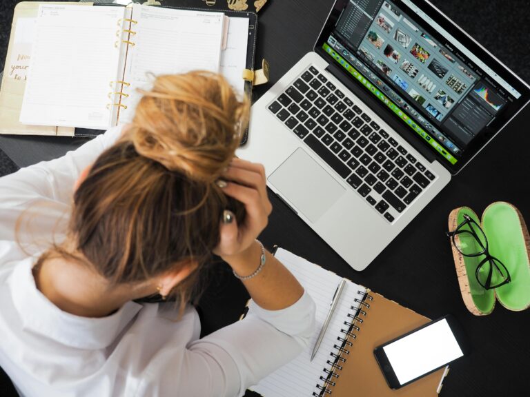 Young entrepreneur stressed while planning business at desk with laptop and documents