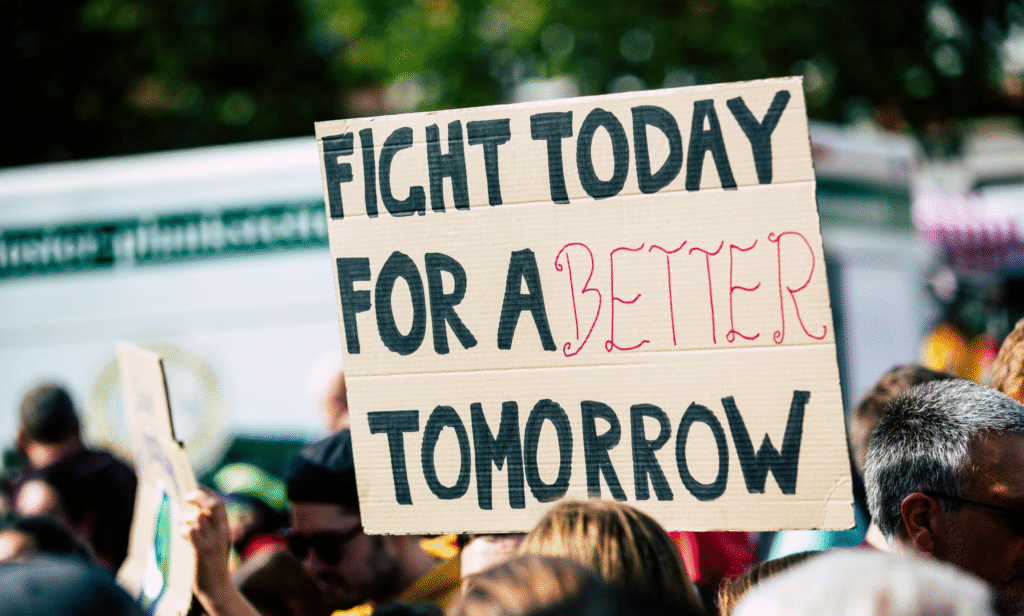 Protesters holding a banner with the slogan 'Fight Today for Better Tomorrow' during a rally.