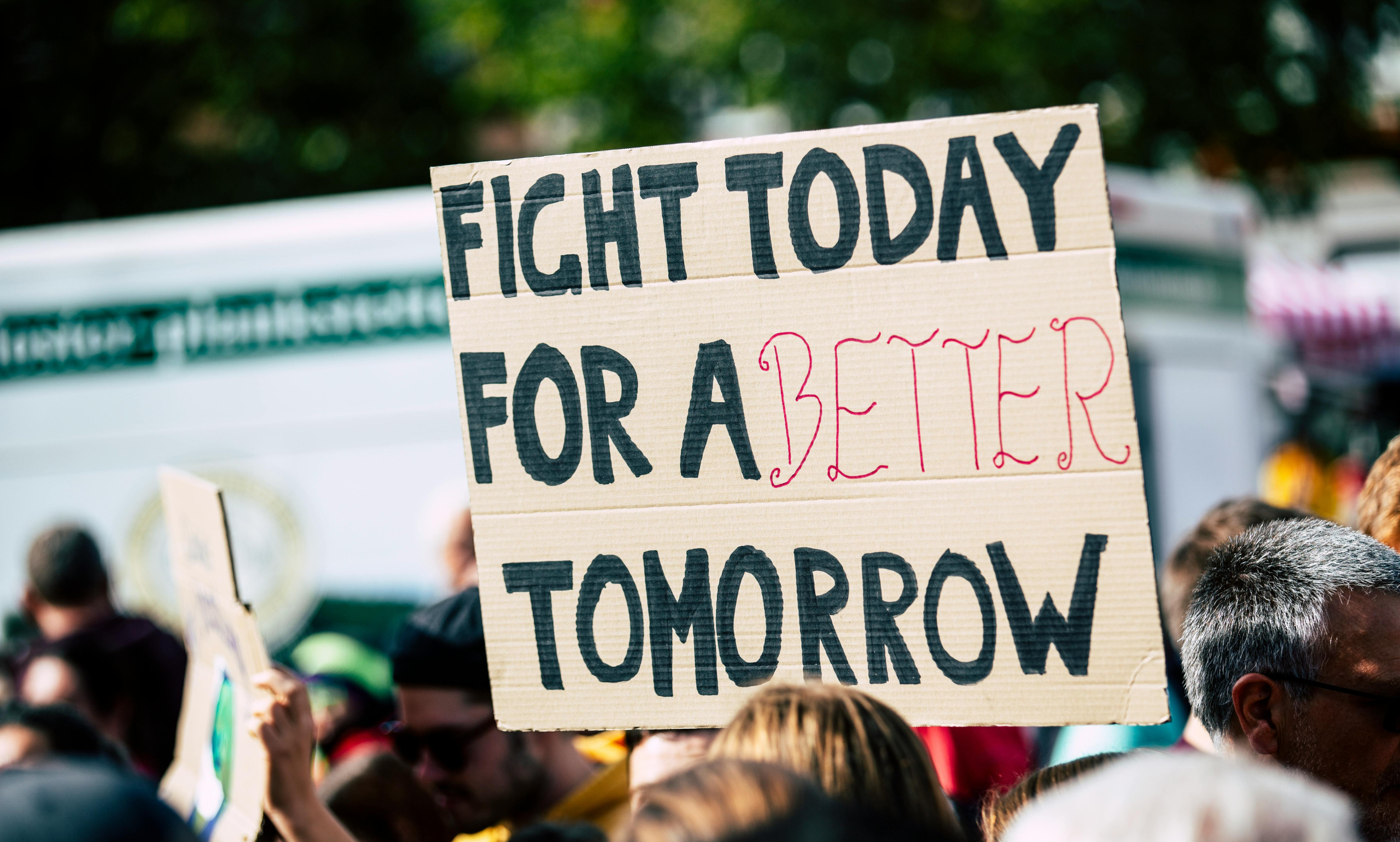 Protesters holding a banner with the slogan 'Fight Today for Better Tomorrow' during a rally.
