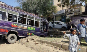 Damaged bus and car after a road accident in Pakistan with children nearby on the street